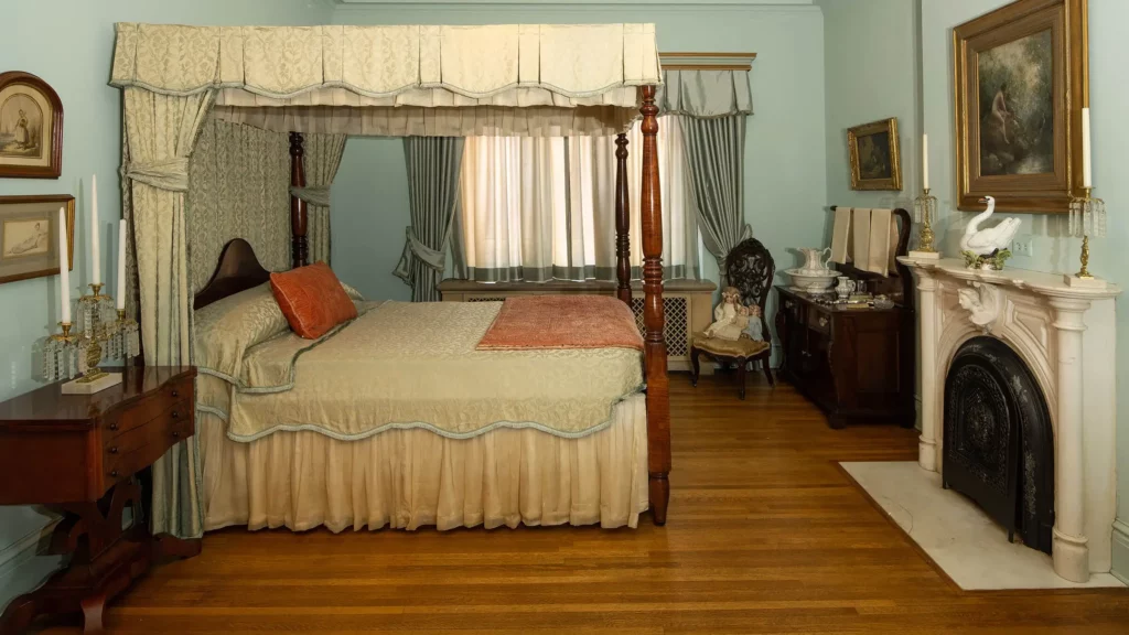 The Guest Bedroom features a four-poster canopy bed, light turquoise walls, and a marble fireplace.