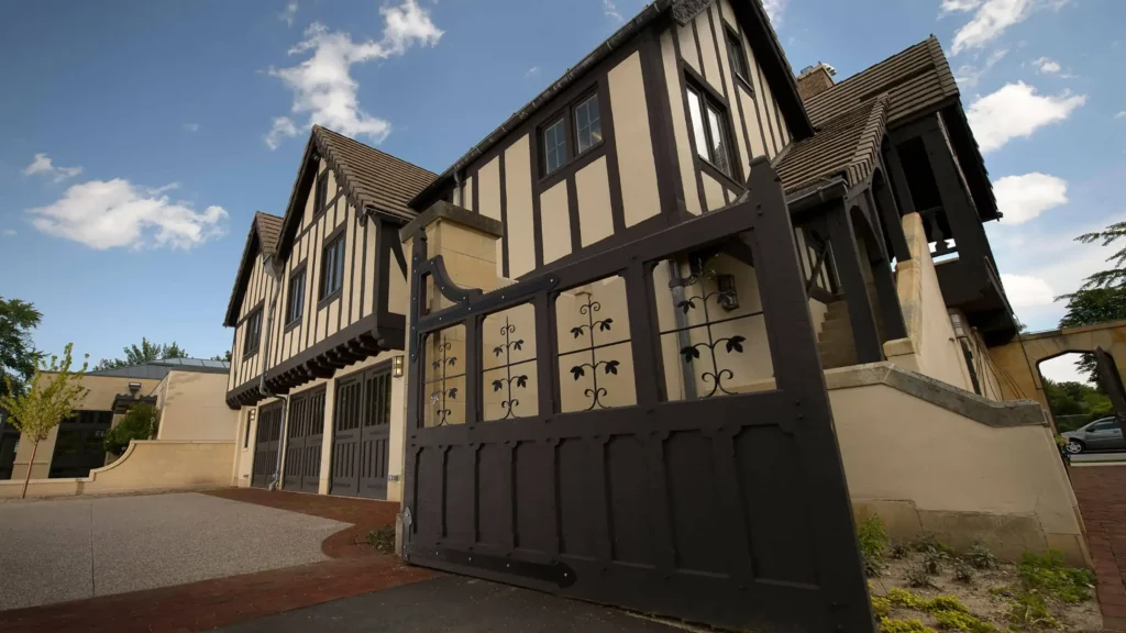 The Tudor-style Carriage House with historic garage doors and an outdoor staircase to the second floor.