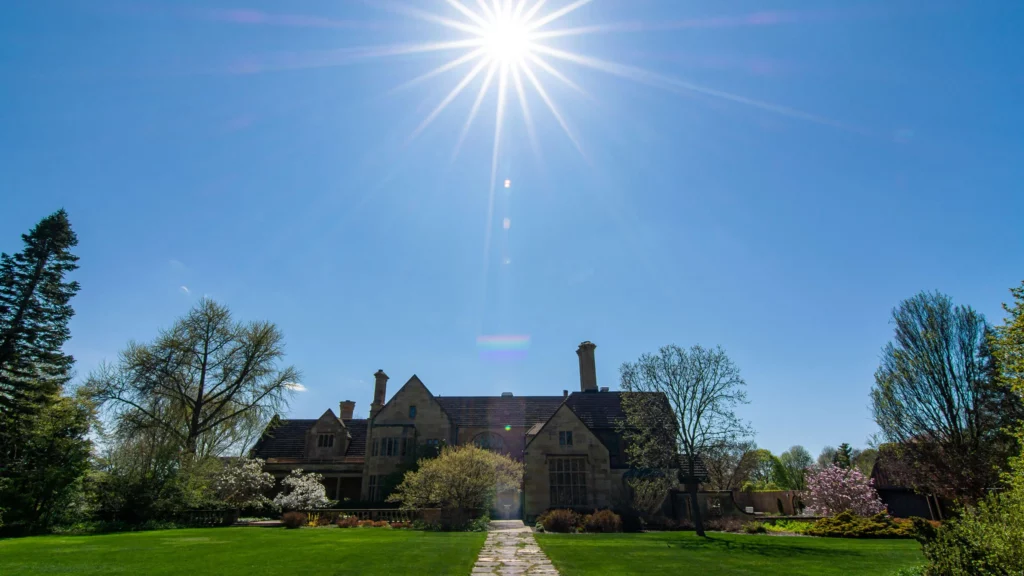 The sun shines over the back façade of the mansion and Great Lawn in springtime.