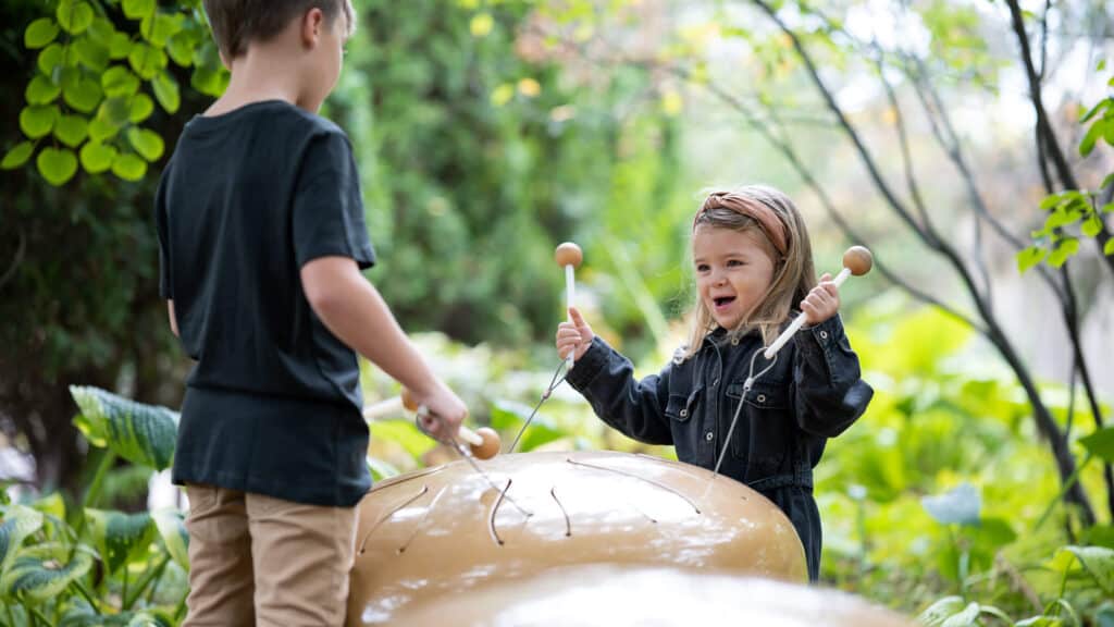 A girl and boy play with mushroom-shaped drums in the Children’s Garden. Photo by Mirrorless Productions.