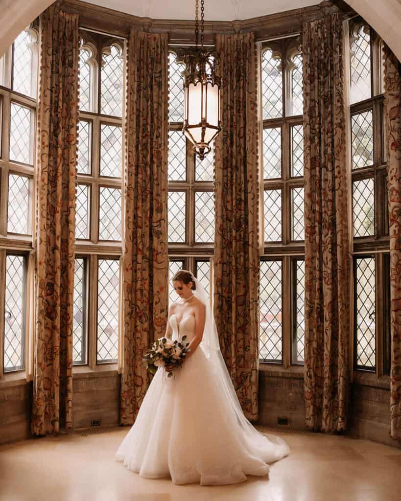 A bride poses for a photo in the alcove of the mansion’s Great Hall.
