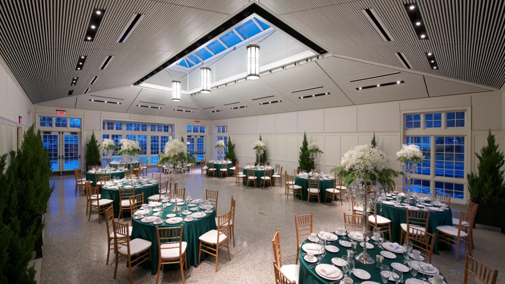 The Conservatory set up for an event with round tables, teal linens, and white flowers.