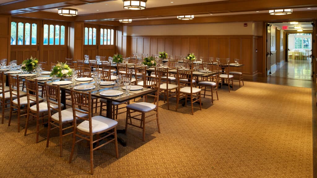 The Carriage House set up for an event with long tables and greenery.