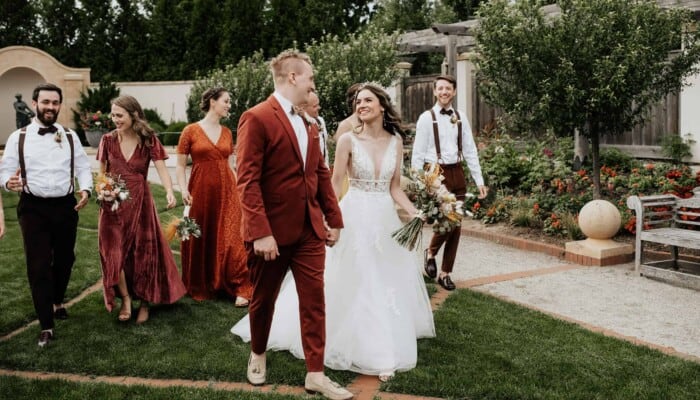 A couple walk with their bridal party in the Formal Garden.