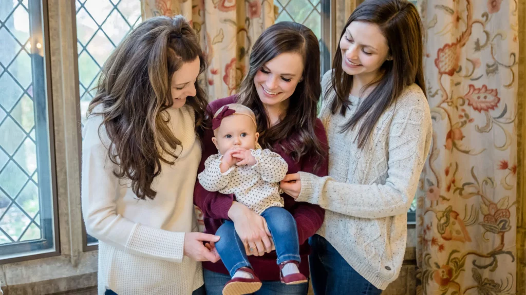 Three women smile with a baby