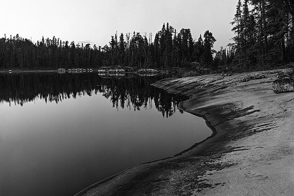 A sandy beach meets the water of a lake.