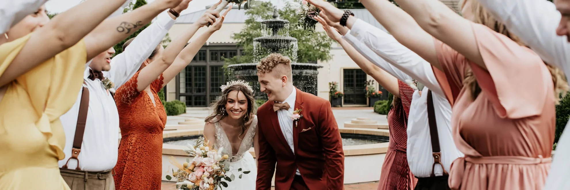 A bride and groom walk through a tunnel created by their bridal party in the Formal Garden.