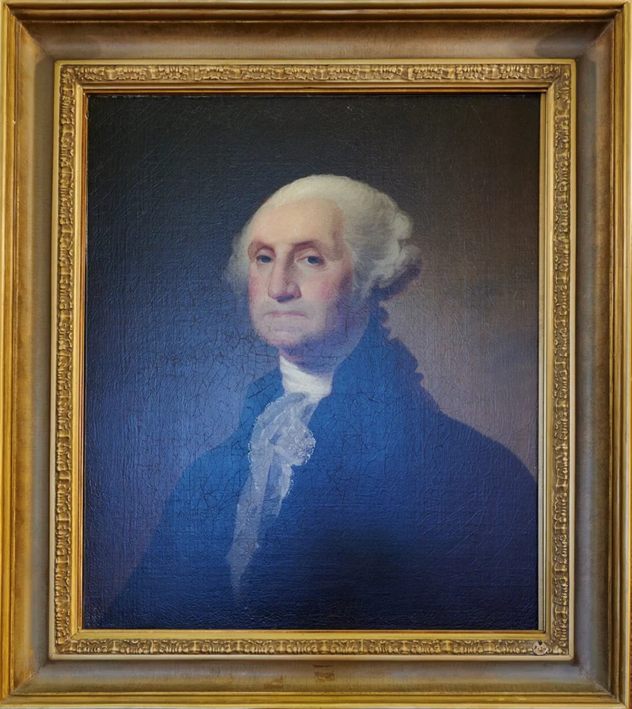 A portrait of George Washington in a simple black coat with a white ruffle shirt.