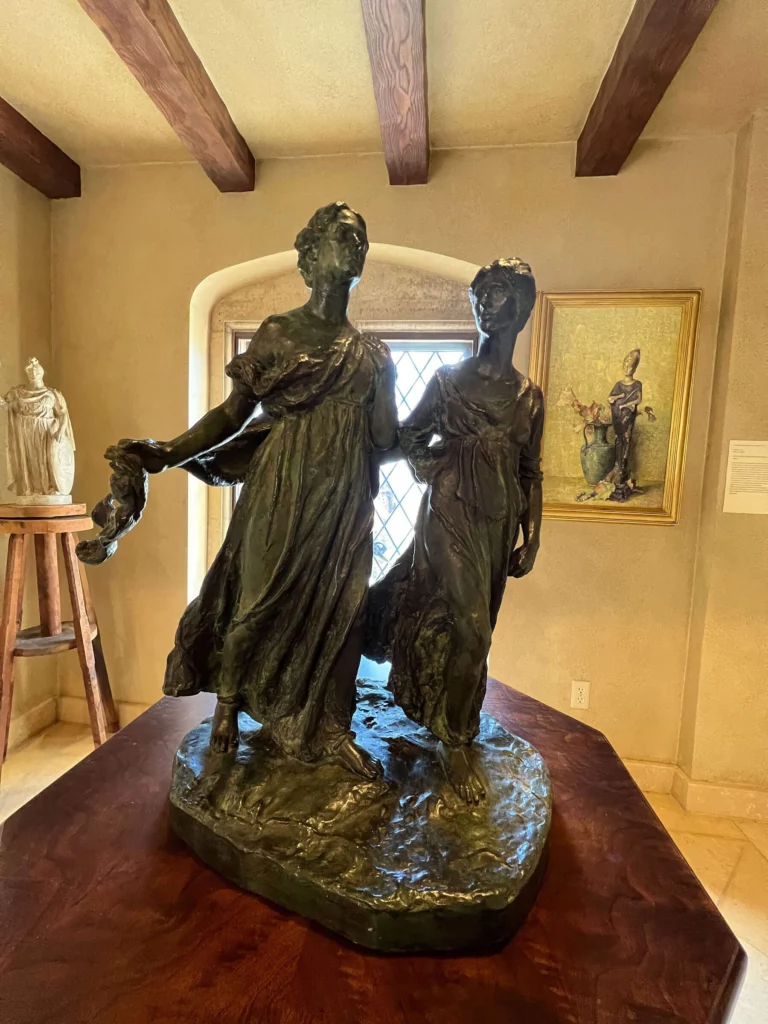 A sculpture of two women who appear to glide forward, with uplifted gaze and drapery afloat.