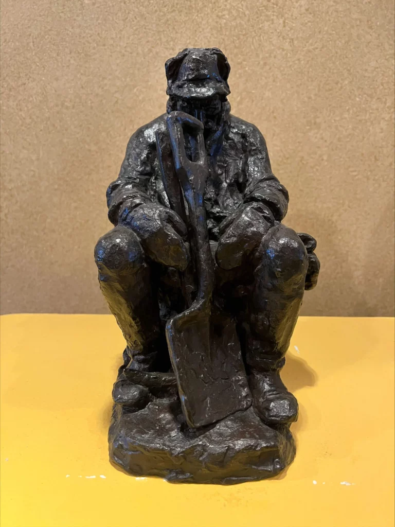 A sculpture of a miner slumped over with his shovel.