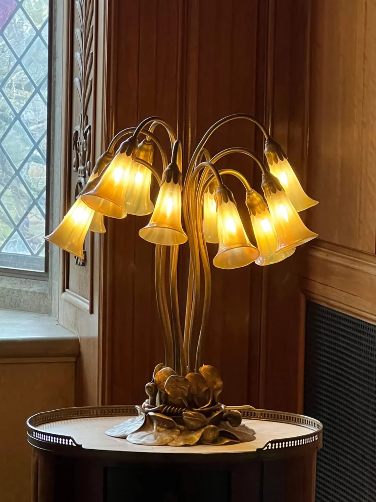 A leaded glass and bronze floor lamp with multi-hued white blossoms on a mottled green ground.