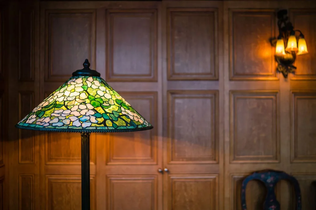 A leaded glass and bronze floor lamp with multi-hued white blossoms on a mottled green ground.