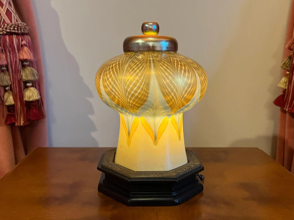 A small yellow table lamp with a “pull-feather” motif outlined in gold.
