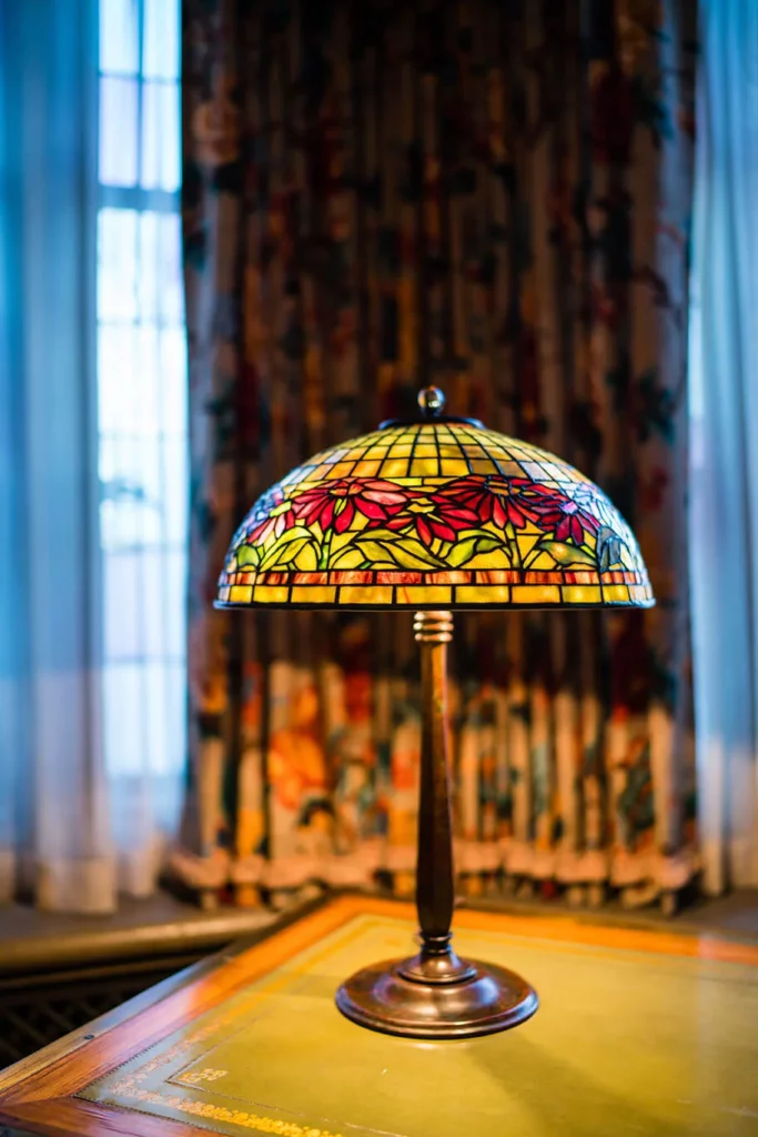 A leaded glass and bronze table lamp with yellow hues and magenta Poinsettia flowers.