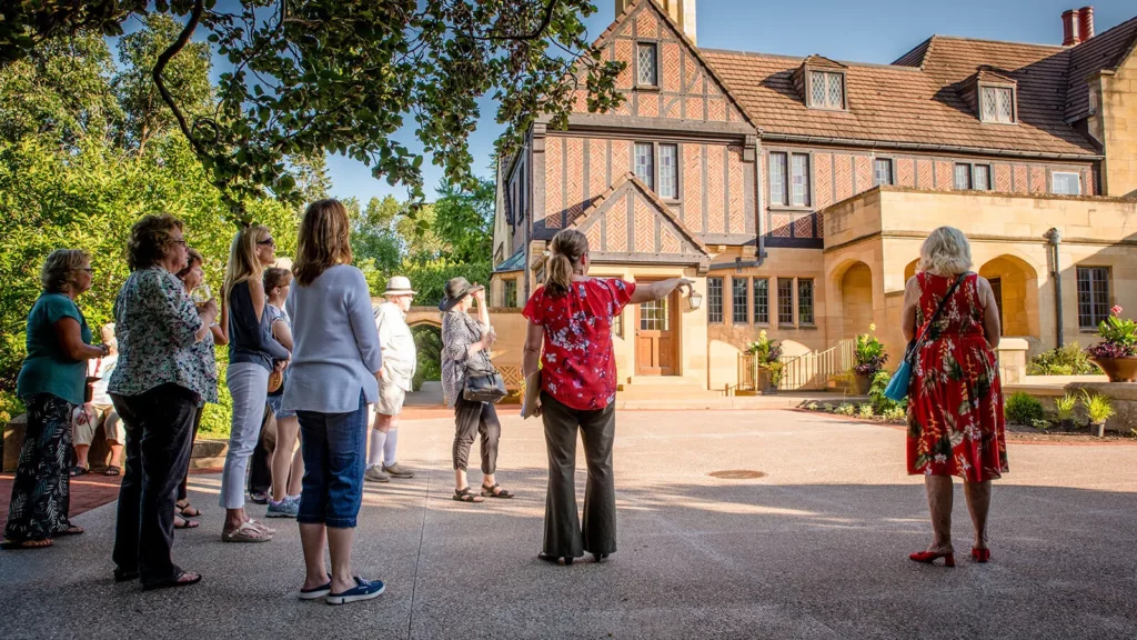 A group of people view the mansion in summertime.