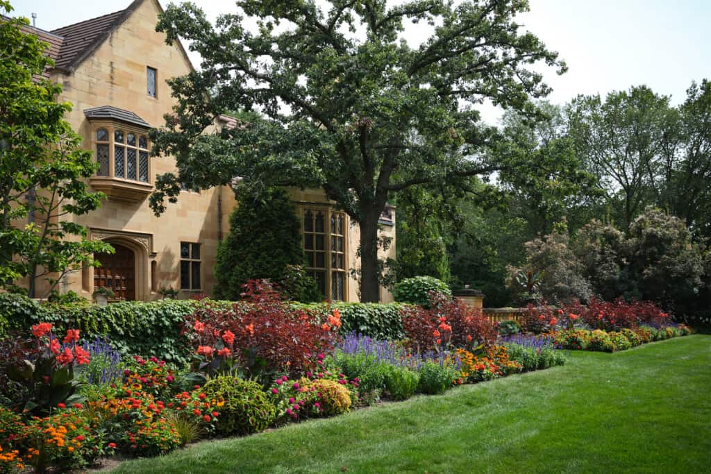 The front façade of the mansion with plants and flowers in full bloom during late summer.