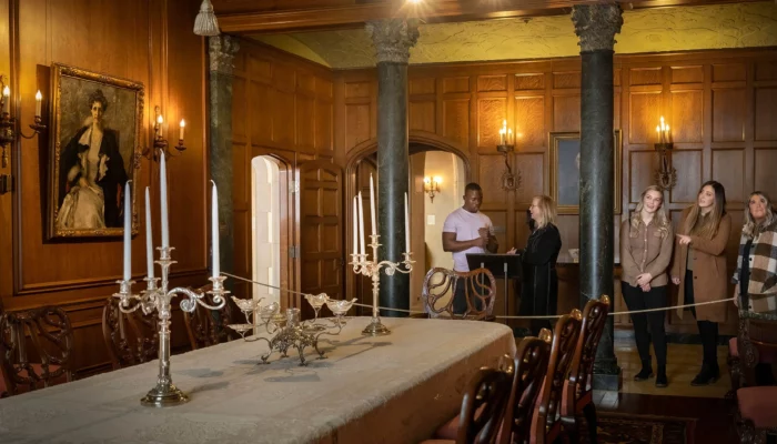 A group of people view the Dining Room in the mansion.