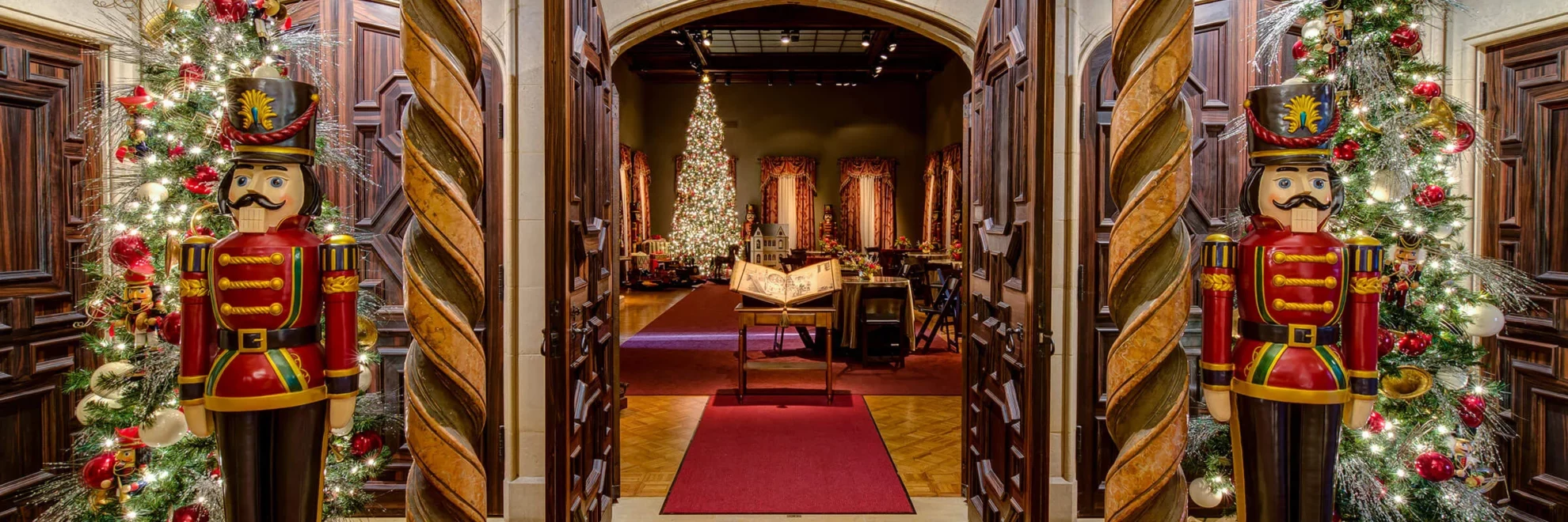 The Main Gallery and foyer during Nutcracker in the Castle, with life-size Nutcrackers, Christmas trees, and a room decorated in the background.