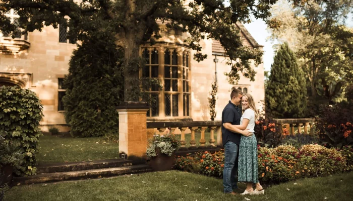 A couple embrace near a garden bed on the front lawn.