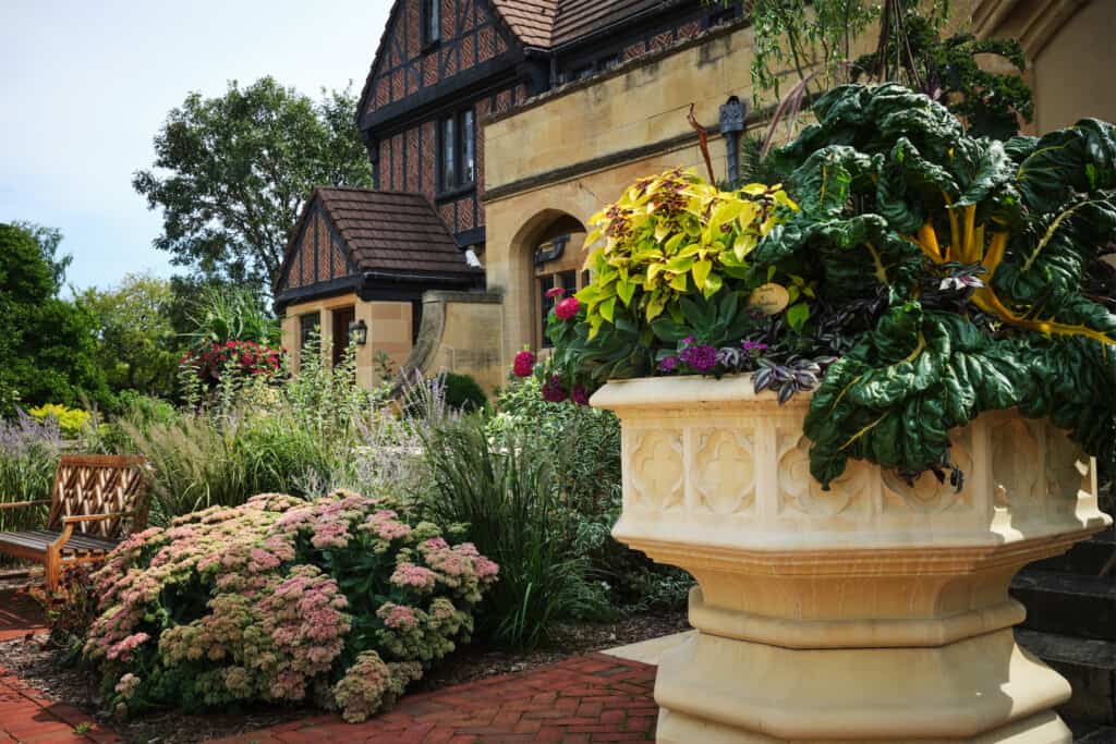 The North Court of the mansion features perennials and grasses, with a large planter filled with green plants.
