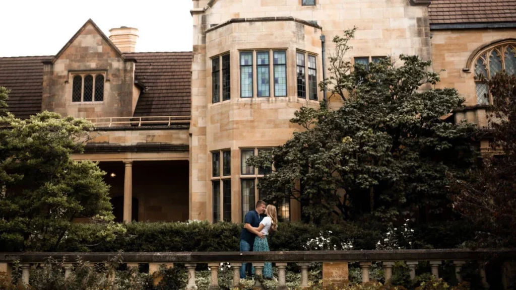 A couple poses for a photo outside the mansion.