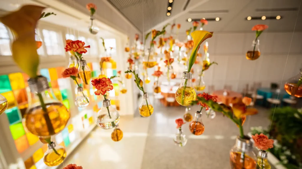 Individual flowers hang from the ceiling in the Conservatory in lightbulbs filled with orange and yellow hues of water.