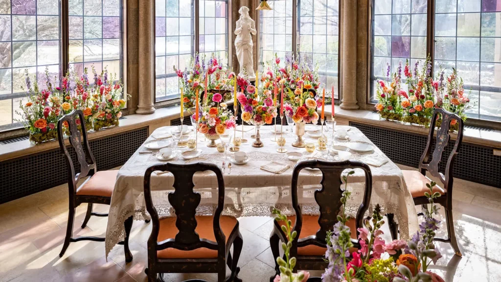 The Breakfast Rooms displays in bright pink and orange flower arrangements, with the sun shining in through stained-glass windows.