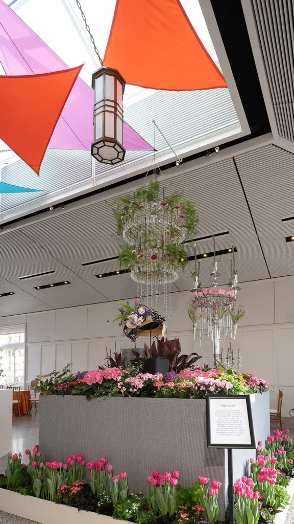 A monumental display of pink and magenta flowers towers in the Conservatory while chandeliers bursting with florals hang above.