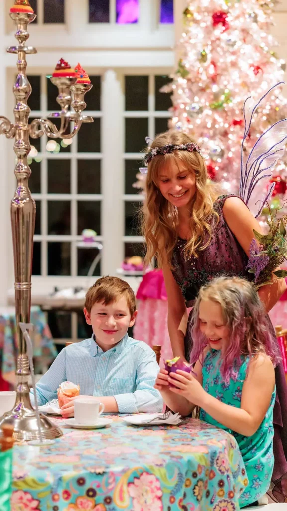 The Sugar Plum Fairy greets two children eating cupcakes in the cafe.