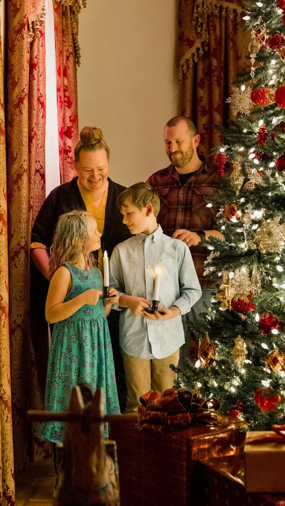 A family of four pose for a photo next to the giant Christmas tree in the Opening Party scene.