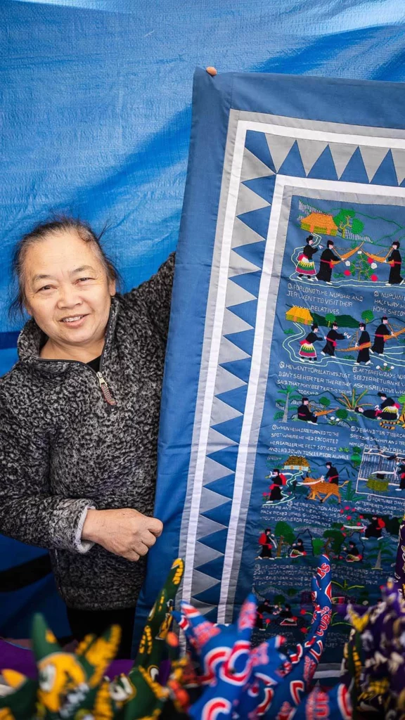 Artist Mao Lor holds a paj ntaub she created.