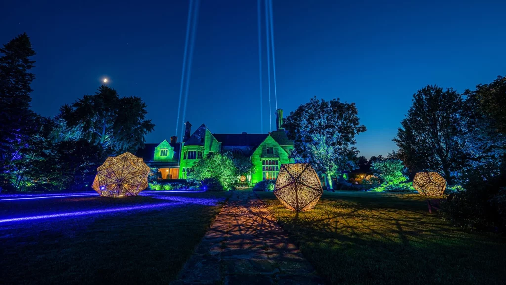 The Great Lawn of the Paine illuminated in green, blue, and yellow lighting, with three large geometric sculptures.