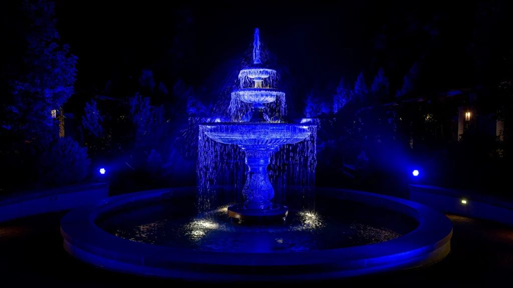 A water fountain is illuminated in royal blue lighting.