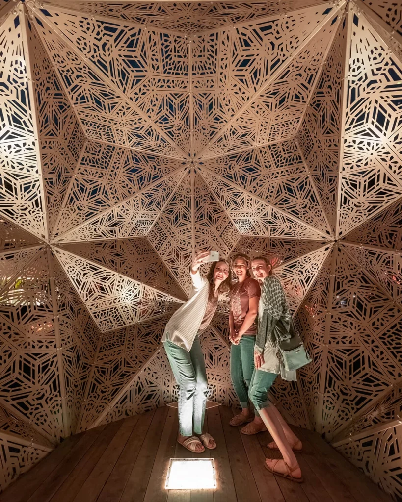Visitors pose for a photo inside a geometric sculpture.