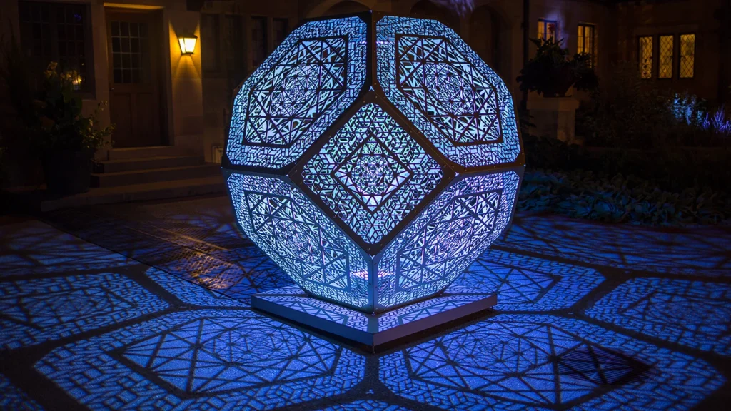 A geometric sculpture is illuminated at night.