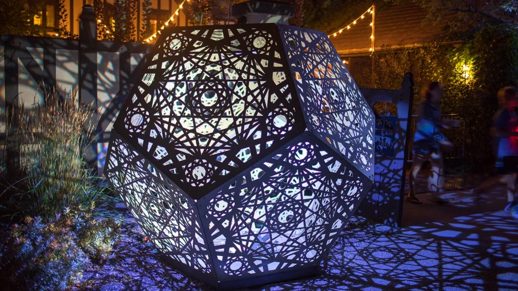 A geometric sculpture is illuminated at night.