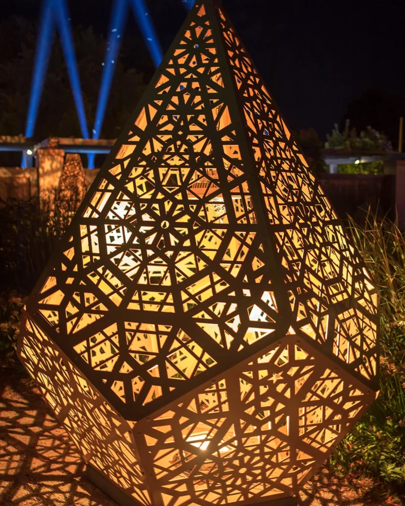 A geometric sculpture is illuminated at night.