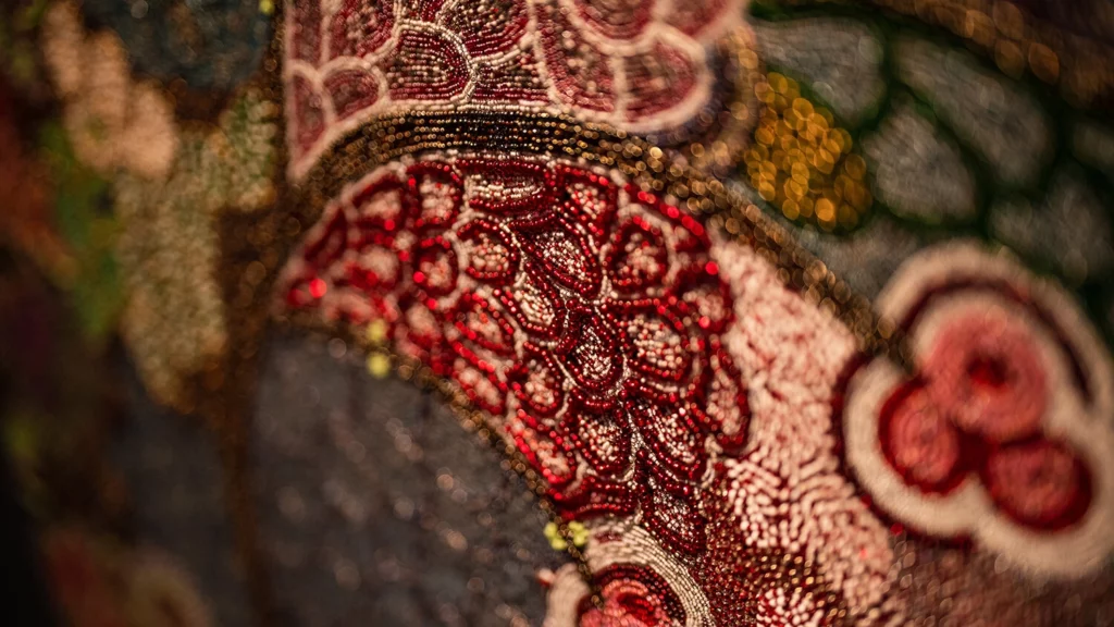 A close-up of colorful maroon and pink glass beads featured in a ndwango, or beaded artwork.