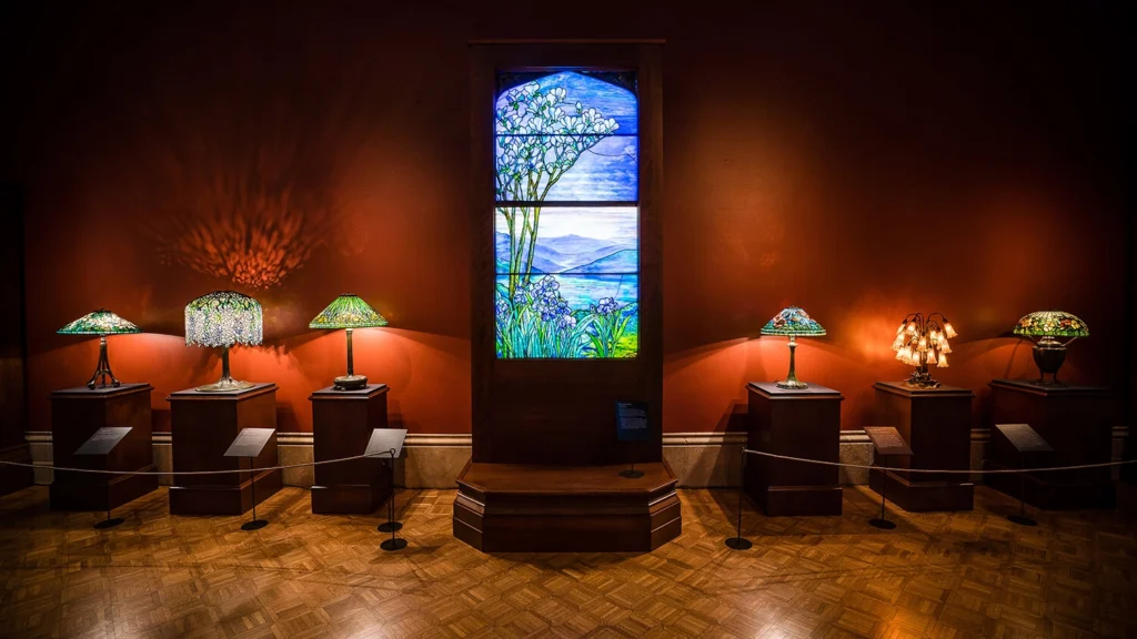 A stained glass window with three stained glass lamps on either side.