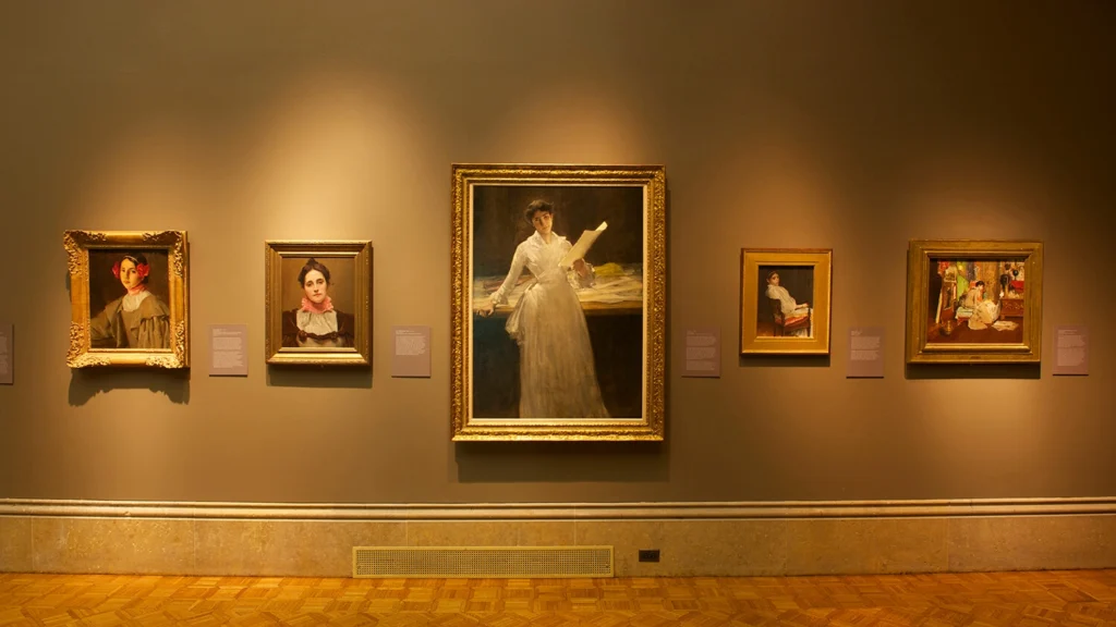 Artworks by William Merritt Chase hang on a wall.