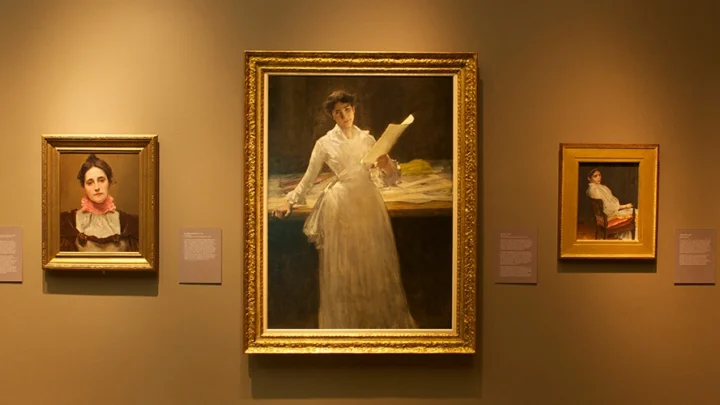 Artworks by William Merritt Chase hang on a wall.