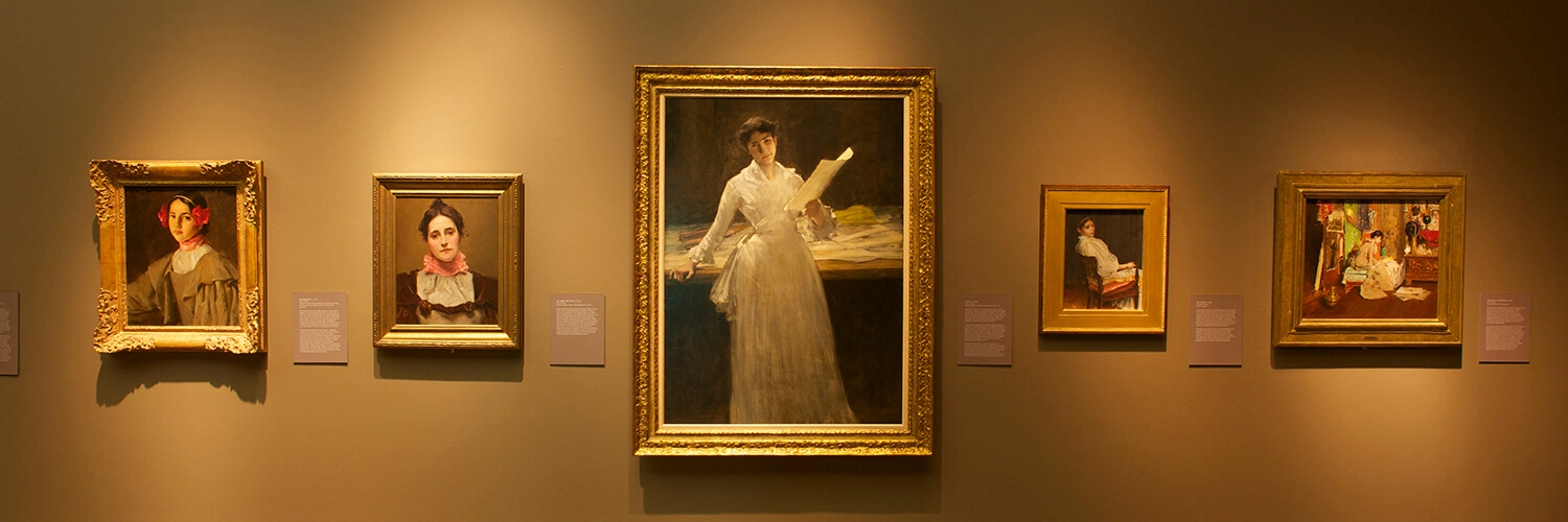 Artworks by William Merritt Chase hang on a wall.