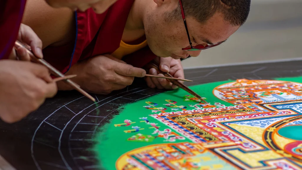 A Tibetan monk works on a sand mandala.