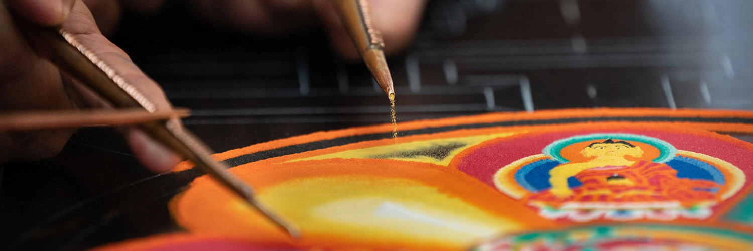 A funnel and striker disperse sand to create a mandala.