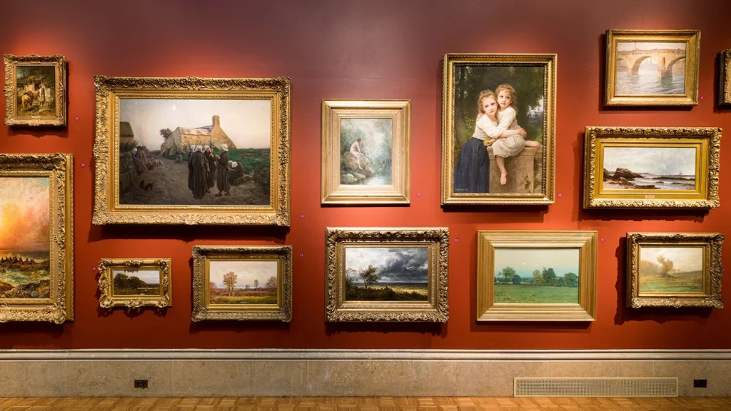 A view of the main gallery featuring a salon-style hanging of masterpiece artworks.