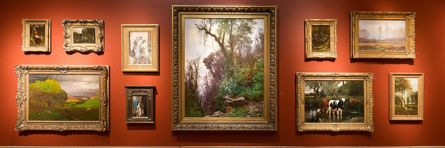 A view of the main gallery featuring a salon-style hanging of masterpiece artworks.