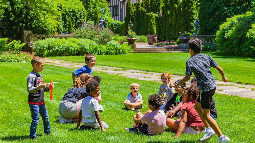 Children play "duck, duck, goose" on the Great Lawn at the Paine.