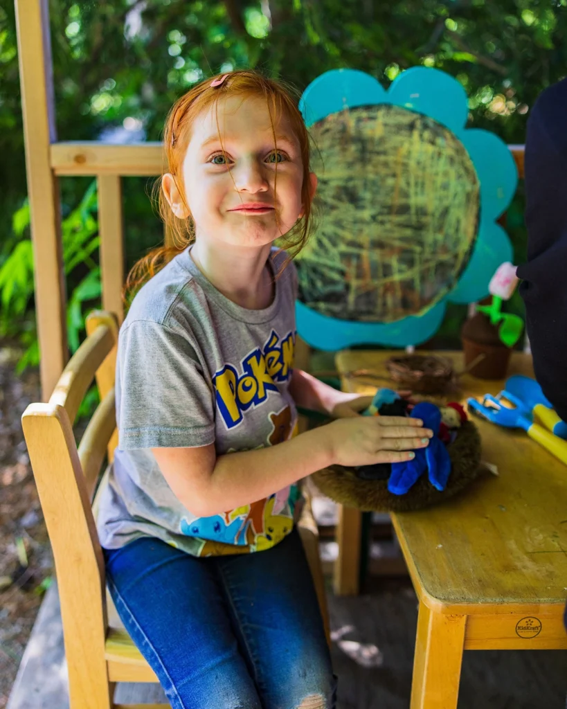 A girl plays at a field station in the gardens at the Paine.