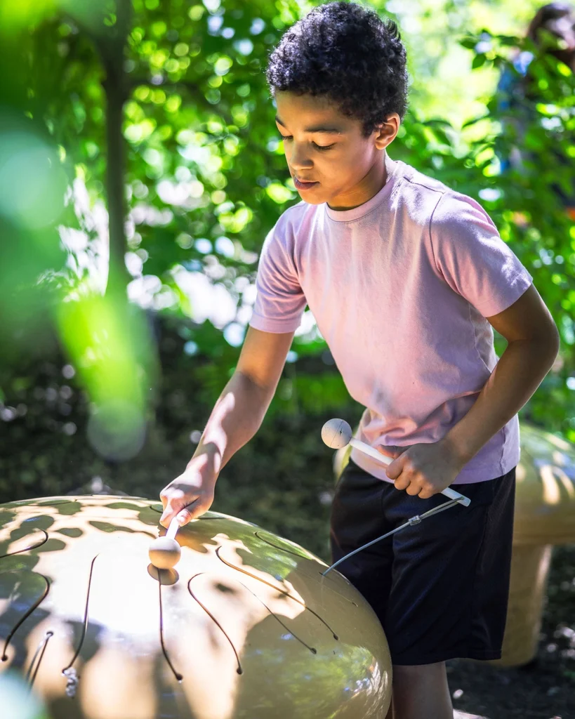 A child plays a mushroom-shaped moringa in the gardens at the Paine.