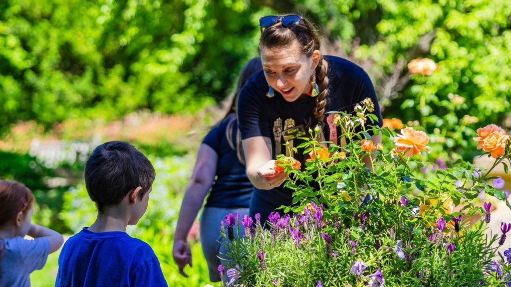 A woman shows a boy a flower.